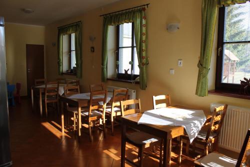 una sala da pranzo con tavoli, sedie e finestre di Penzion Fialka a Velké Losiny