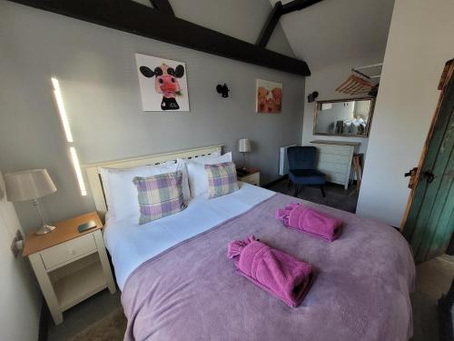 a bedroom with a large bed with purple sheets and pillows at Bonneys Barn Retreat - Luxury homely getaway in Burgh Saint Peter