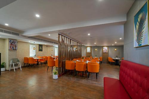 a dining room with orange chairs and tables at THE PORT BY JDANIELS in Trivandrum