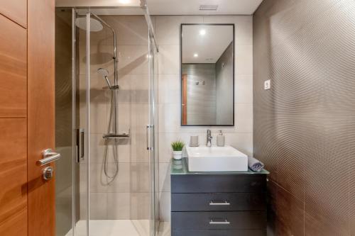 La salle de bains est pourvue d'un lavabo et d'une douche avec un miroir. dans l'établissement Modern 2 bedroom apt 20 min from city center, à Amadora