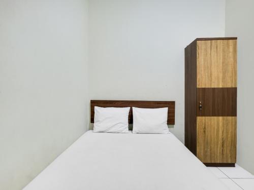 um quarto com uma cama branca e um armário de madeira em SPOT ON 2451 Camel Residence em Semarang