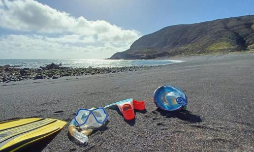 a pair of goggles and a surfboard on a beach at Mar de Lava Sunrise Fuerteventura in Pozo Negro