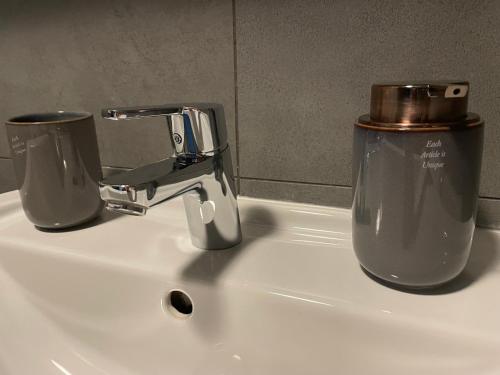 a sink with a faucet and two cups on it at Garden Apartman Radnica in Košice