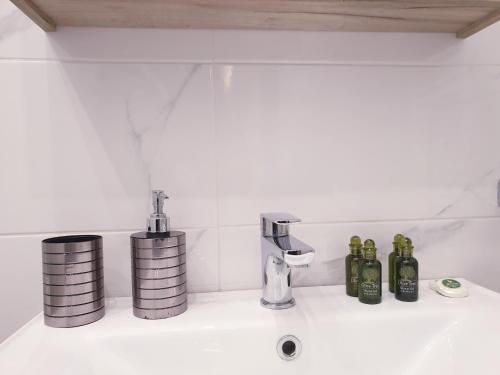 a bathroom sink with bottles and a faucet at Eantos Studios and Suites in Perea