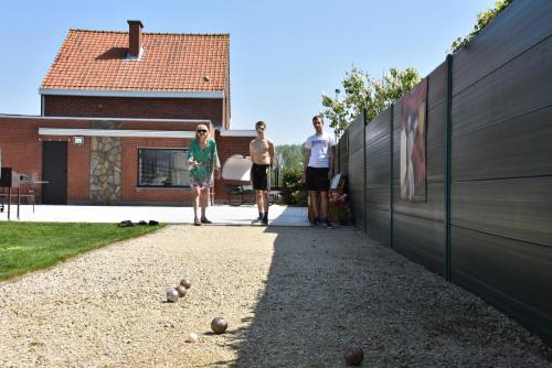 three people standing next to a fence with balls on the ground at Casa D&N in Passendale