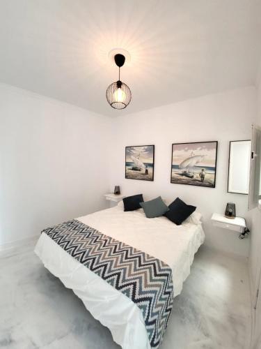 een witte slaapkamer met een groot bed en een lamp bij Mar Bonanza in Orzola