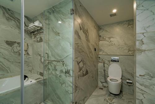 a bathroom with a shower and a toilet and a tub at THE PORT BY JDANIELS in Trivandrum
