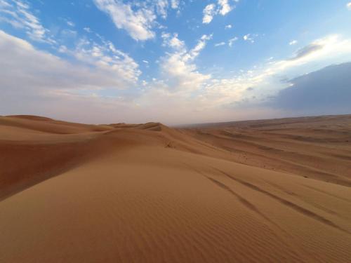 a desert with sand dunes and a blue sky at Desert Moments Glamping - full privacy in Muntarib