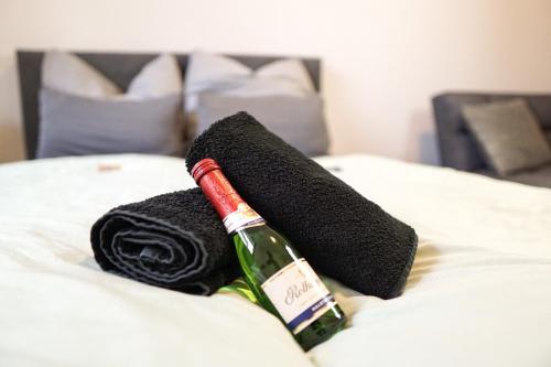 una bottiglia di vino e un asciugamano sul letto di HOMY I Altbaucharme Netflix und WLAN a Lipsia