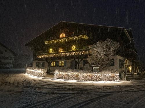 a house covered in christmas lights in the snow at Landhaus Speiser in Bolsterlang