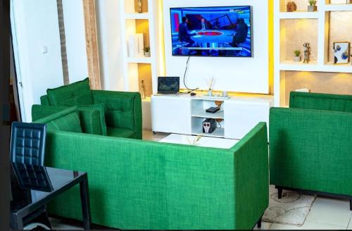 a living room with green couches and a tv at Appartement cosy Green bonapriso in Douala