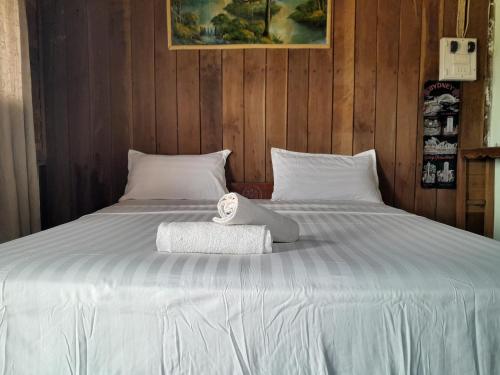 een groot wit bed met een handdoek erop bij Rivergarden Guesthouse and restaurant in Don Det