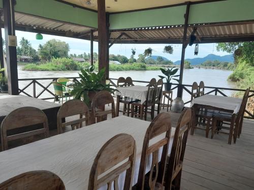 a restaurant with tables and chairs next to a river at Rivergarden Guesthouse and restaurant in Don Det