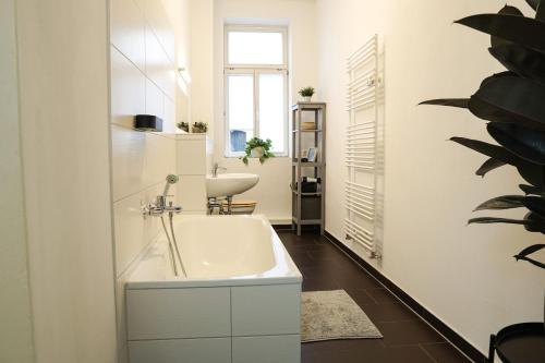 een badkamer met een wit bad en een wastafel bij HOMY I Altbaucharme Netflix und WLAN in Leipzig