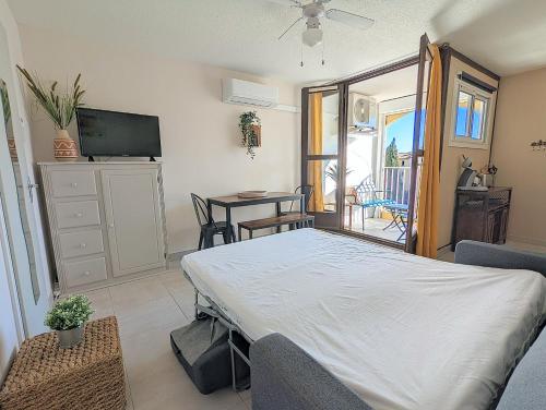 - un salon avec un lit et une table avec des chaises dans l'établissement Appartement avec WIFI et CLIMATISATION, proche golf et île des loisirs, au Cap d'Agde