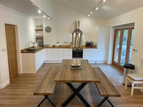 a kitchen with a wooden table in the middle at Redstones Cottage in Greasby