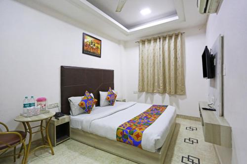 a bedroom with a bed and a table and a tv at Hotel Sterling Inn, New Delhi in New Delhi
