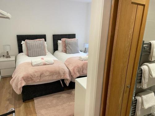 a bedroom with two beds with pink pillows at Redstones Cottage in Greasby