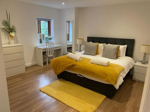 a bedroom with a large bed with a yellow blanket at Redstones Cottage in Greasby