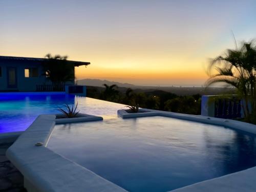 a swimming pool in front of a house with a sunset at Hotel Eclipse, Playa Coronado in Playa Coronado