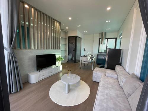 a living room with a couch and a tv and a table at Marina Golfview in Ðố Sơn