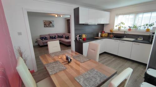 a kitchen and dining room with a wooden table in a room at Lovely 2 Bedroom Modern Ground Floor Flat in Clydebank