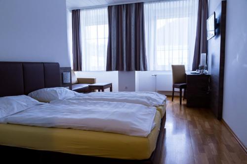 a hotel room with a bed and a couch and windows at Hotel Vinothek Schwarzer Adler in Ottensheim