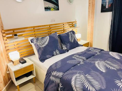 a bedroom with a bed with blue and white blankets and pillows at Appartement cosy Green bonapriso in Douala