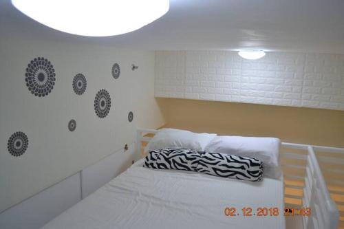 Una cama blanca con una almohada blanca y negra. en SMDC Wind Residences 102 Loft Bedroom Facing Amenities with WIFI and Parking en Tagaytay