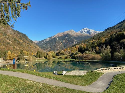 two people sitting by a lake with mountains in the background at Chalet Greuffa in Courchevel