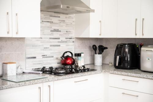 a kitchen with white cabinets and a tea kettle on a stove at Settle inn Self Catering Units in Colchester