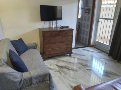sala de estar con sofá y tocador con TV en Casa do Roberto, en Cabo Frío