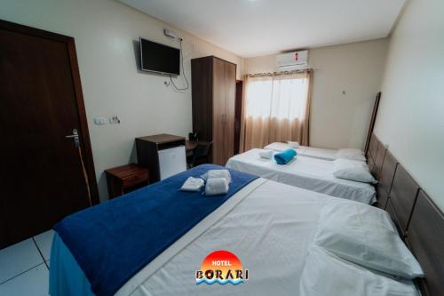 a hotel room with two beds and a television at Hotel Borari in Alter do Chao
