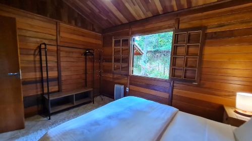 um pequeno quarto com uma cama e uma janela em Chalé Arado 313 em Monte Verde
