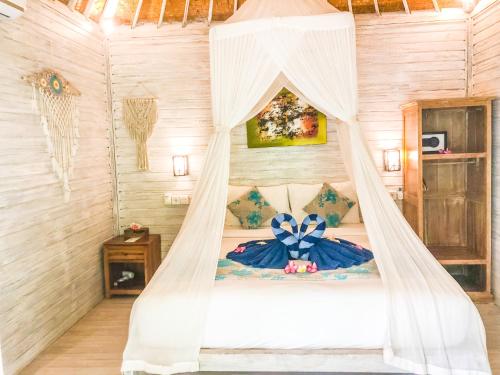 a bedroom with a bed with a mosquito net at The Lucky Cottage in Nusa Lembongan