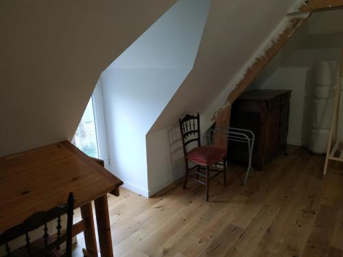 Cette chambre mansardée comprend une chaise, un bureau et un escalier. dans l'établissement Petite chambre - Maison de Maître, à Landéan