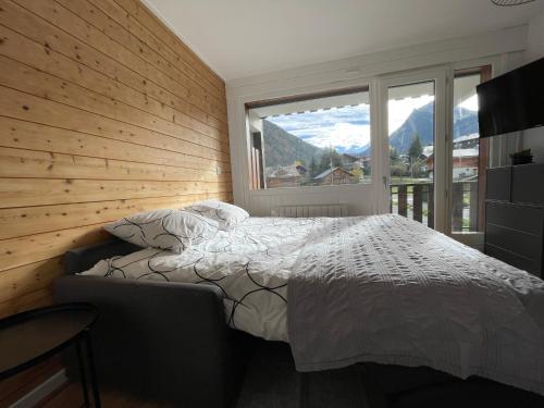 um quarto com uma cama e uma grande janela em Bel appartement rénové, central et skis aux pieds em Morzine
