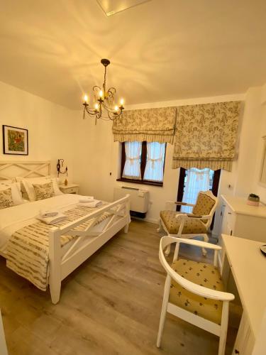 1 dormitorio con cama blanca y lámpara de araña en Pensiunea Charlotte Boutique, en Bacău