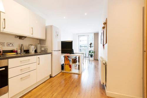 ロンドンにあるLovely room in Modern apartmentの白いキャビネットと木製の床を備えたキッチン