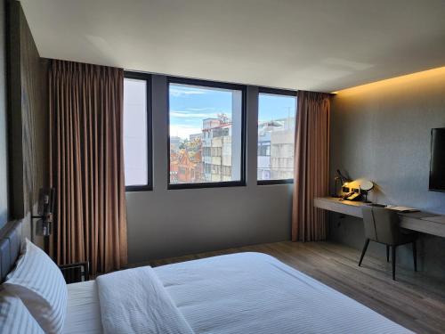 1 dormitorio con 1 cama, escritorio y ventanas en 花蓮品悅文旅Hualien Pink Corner Hotel en Hualien