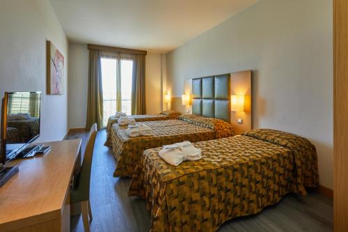 a hotel room with three beds and a desk at Castelmartini Wellness & Business Hotel in Larciano