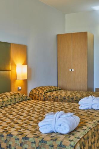 two beds in a hotel room with towels on them at Castelmartini Wellness & Business Hotel in Larciano