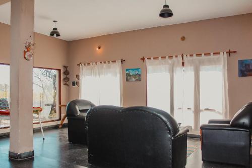 uma sala de estar com cadeiras de couro preto e janelas em EL PEDREGAL Casa en Cafayate em Cafayate
