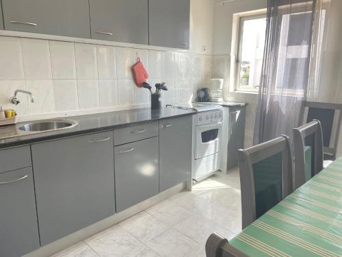 a kitchen with white cabinets and a sink and a stove at Apartamento T2-Dunas Centro in Tarrafal