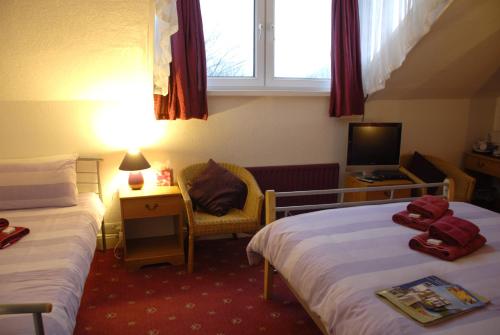 Habitación de hotel con 2 camas y TV en Adam Place Guest House, en Windermere