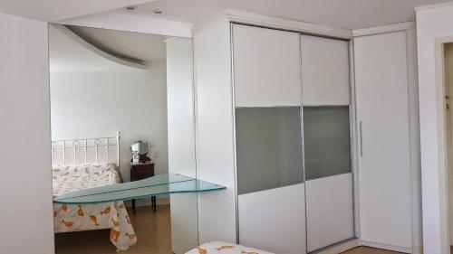 Habitación con mesa de cristal y armarios blancos. en Maravilhoso flat no Leblon, en Río de Janeiro