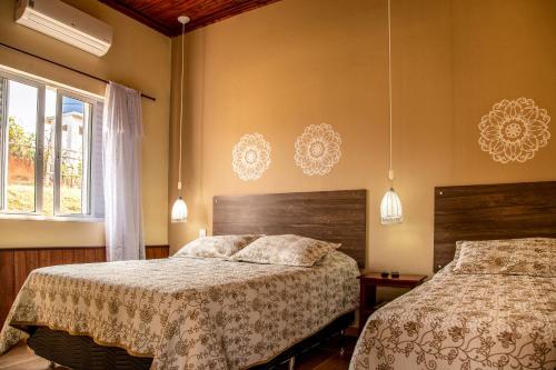 a bedroom with two beds and a window at Pousada Lua Luana in Cambuquira