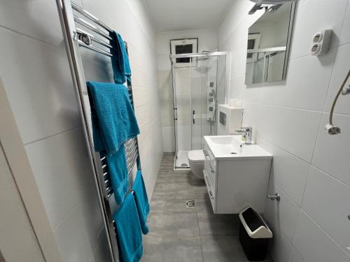 La salle de bains est pourvue d'un lavabo, de toilettes et de serviettes bleues. dans l'établissement Málna Privát Nyaraló, à Balatonlelle
