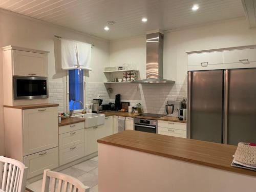 cocina con armarios blancos y nevera de acero inoxidable en Modern 6-bedroom villa near Tampere city, en Tampere