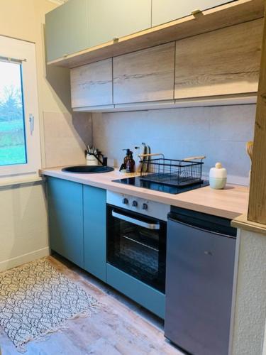 La cuisine est équipée de placards bleus et d'un four avec plaques de cuisson. dans l'établissement La petite halte, à Lemberg